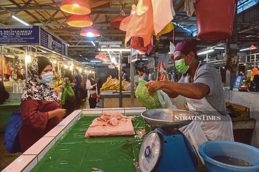 A shopper and a trader adhering to the standard operating procedures at the Chow Kit market in Kuala Lumpur yesterday.  PIC BY AZLIM MANSOR