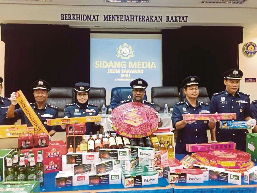 Customs Department director-general Datuk Seri Subromaniam Tholasy (centre) with the seized cigarettes, liquor and fireworks at the state Customs Department office in Sibu on Wednesday. PIC BY HARUN YAHYA