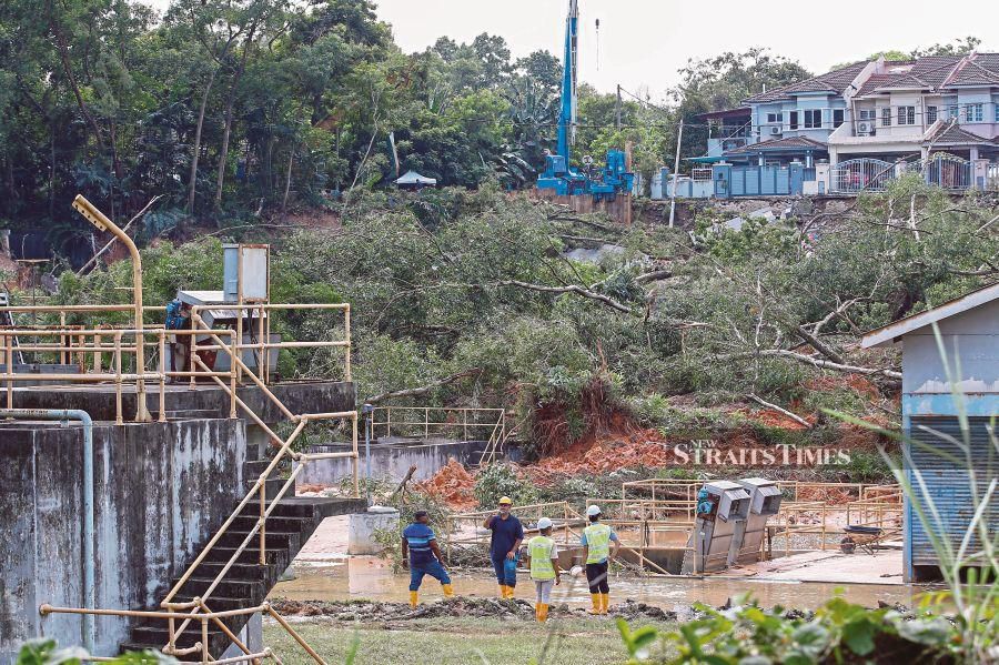 Workers at an Indah Water Konsortium waste treatment plant observing damage to the premises due to a landslide in Taman Wawasan, Puchong, on Dec 16. PIC BY AIZUDDIN SAAD