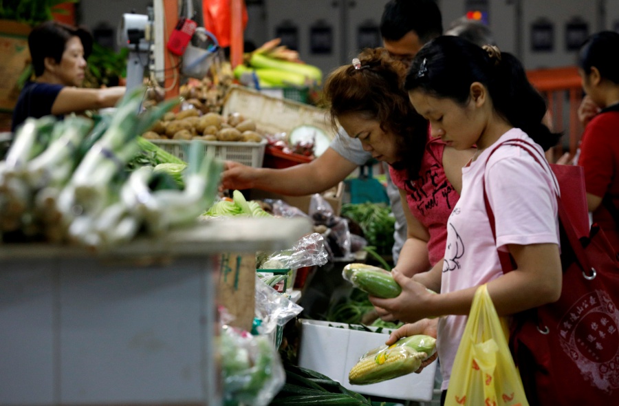 FILE PHOTO: People shop for vegetables at a wet market. REUTERS/Edgar Su