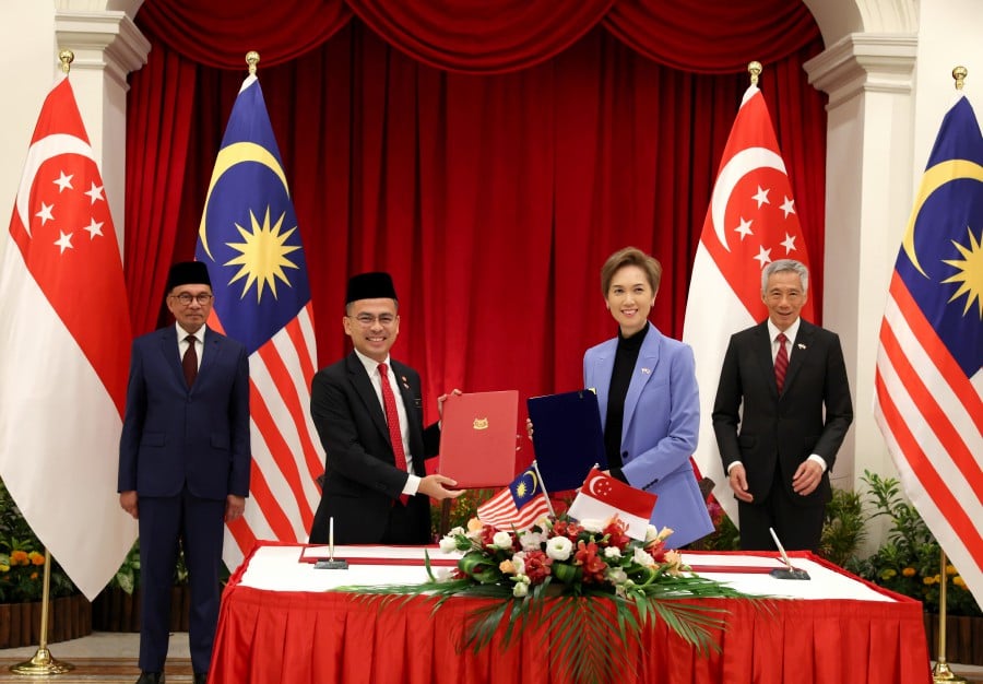 Prime Minister Datuk Seri Anwar Ibrahim (left) and his counterpart from Singapore Lee Hsien Loong (right) witness Memorandum of Understanding on promoting Cooperation in Data, Cyber Security and Digital Economy signing ceremony between Malaysian Communications and Digital Minister Fahmi Fadzil (second, left) and his counterpart from Singapore, Josephine Teo (second, right) at the Istana today. -Bernama pic