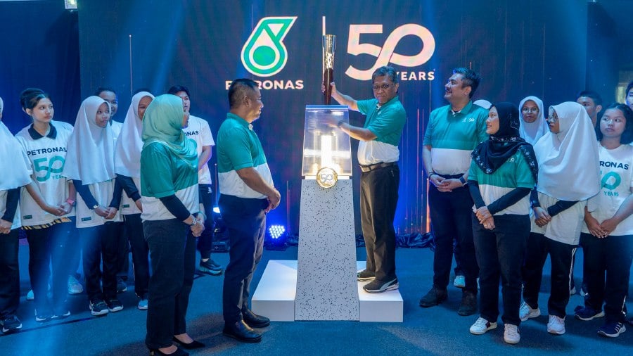 Petronas Malaysia Petroleum Management senior vice president Datuk Bacho Pilong (centre) placing the torch on its pedestal during the inauguration event today, accompanied by (front row from left) General Manager of PETRONAS Sabah and Labuan Regional Office Siti Ayu Abdul Wahab; PETRONAS Chemicals Methanol Sdn Bhd CEO Hiffani Mohd Jalil; General Manager of Human Capital Investment Syed Mohammad Muhafiz Syed Mohd Bakar, and Senior General Manager of Strategic Communications Siti Azlina Abdul Latif, together with students attending the Discover PETRONAS @Schools. PIC COURTESY OF PETRONAS