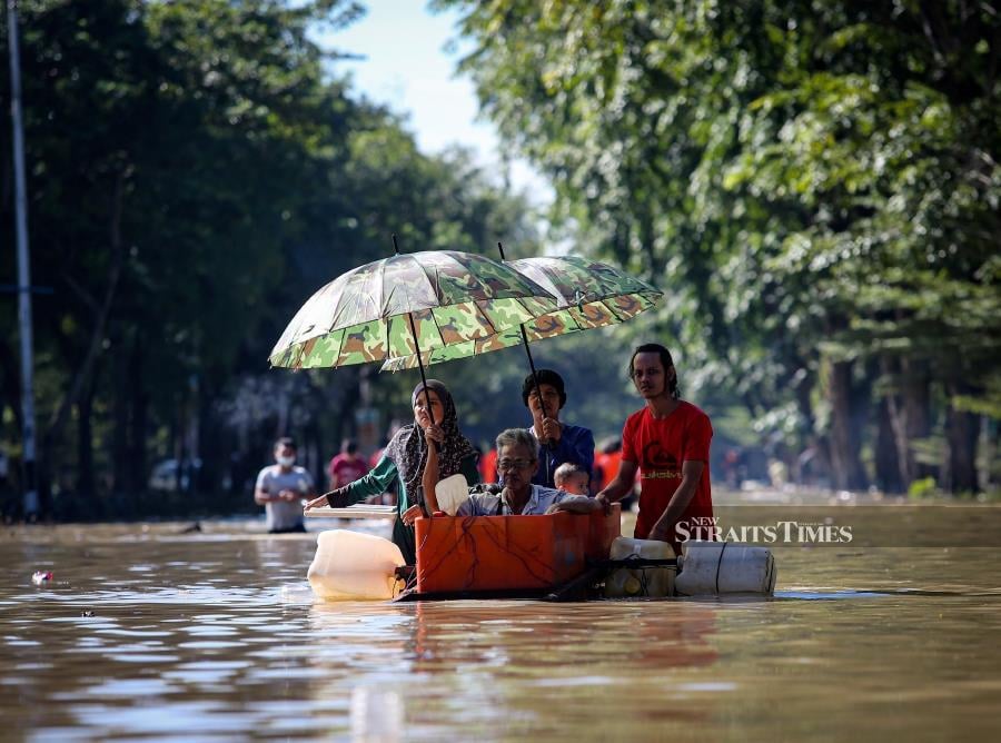 This file pic dated December 21, 2021m shows residents of Taman Sri Muda in Shah Alam using a makeshift boat to wade through floodwaters.  - NSTP file pic