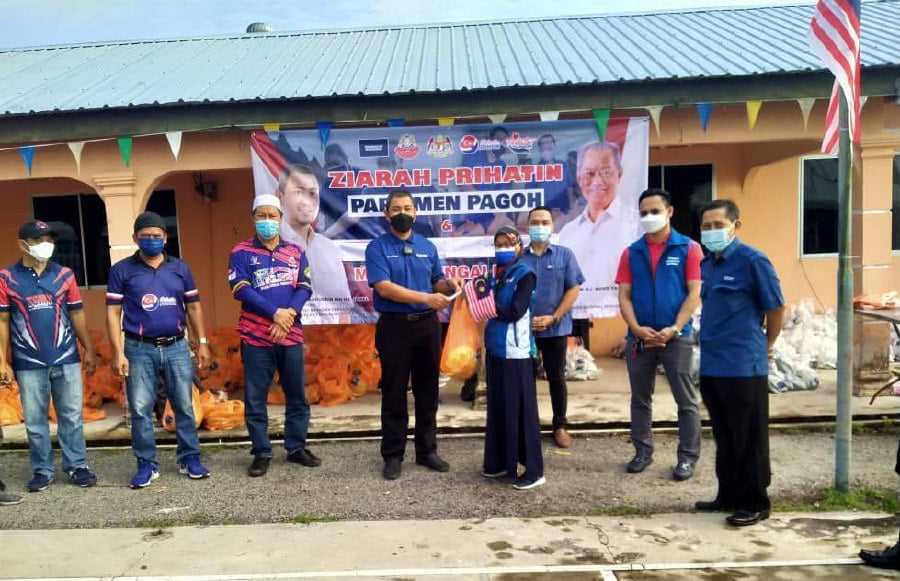 Sahruddin (fourth from left) handing over aid to community heads for distribution in Kampung Melayu, Muar. Looking on is Najib (third from left).