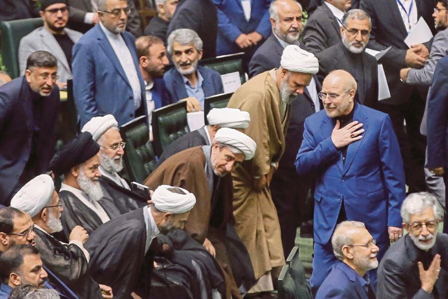 Speaker Mohammad Bagher Qalibaf (right) greeting lawmakers at the opening session of the new Parliament in Teheran, Iran, on Monday. AFP PIC 