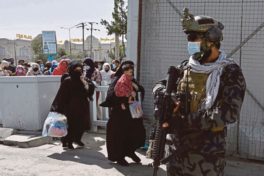 Taliban Badri fighters, a ‘special forces’ unit, guarding as Afghans walk thorough the main entrance gate of Kabul airport to leave Afghanistan on Saturday. - AFP PIC 