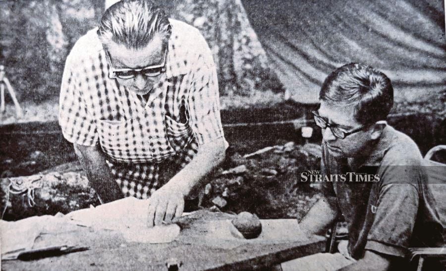 British researcher Tom Harrisson (left) studying prehistoric artifacts dug up in Santubong. 