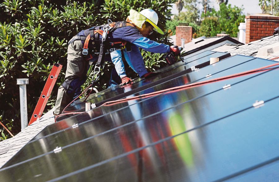 A worker installing a solar panel on the roof of a house in California. AFP PIC 