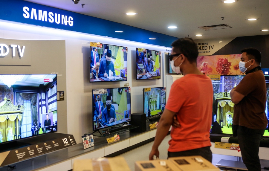 Customers watching  Datuk Seri Ismail Sabri Yaakob’s swearing-in ceremony as the ninth prime minister of Malaysia at an electronics store in Kuala Lumpur, yesterday. -NSTP/HAZREEN MOHAMAD
