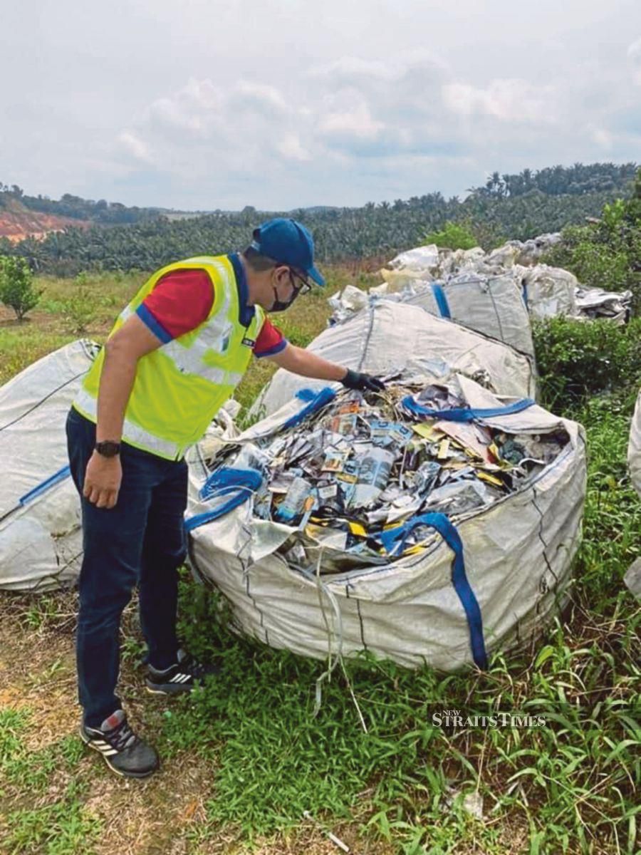  A Department of Environment official inspecting plastic waste illegally dumped in Johor last month. - File pic