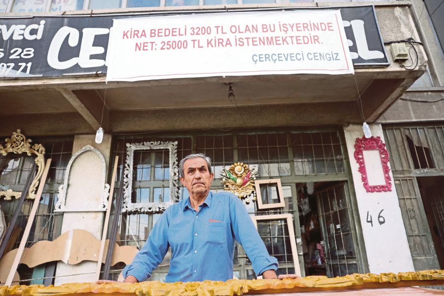 Woodcarver Cengiz Orsel standing in front of his Ankara shop with a banner that reads ‘They have asked to increase my rent of 3200 lira to 25,000 lira’. AFP 