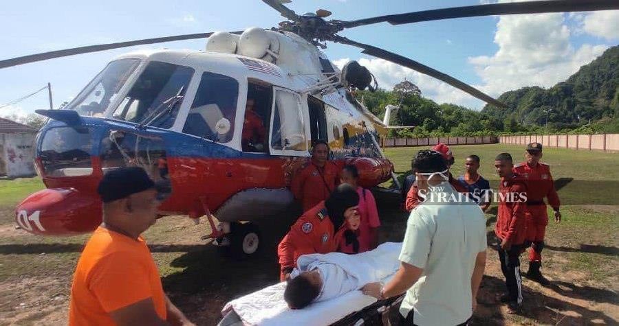 Firemen help evacuate one of the patients from Pos Bihai. - NSTP/Paya Linda Yahya 