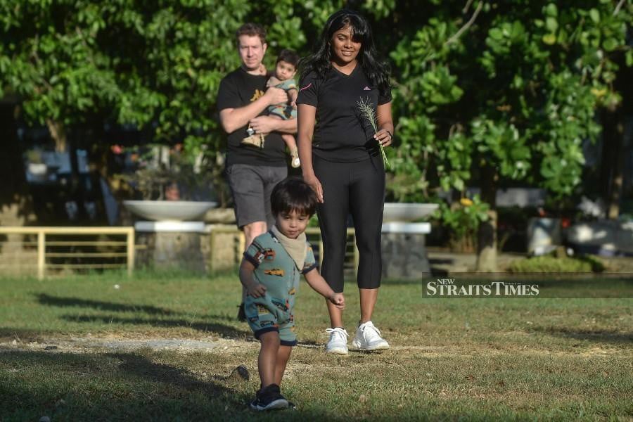 In this photo taken on February 29, 2024, Grace Nathan (R), a relative of one of the missing victims of Malaysia Airlines flight MH370 that disappeared in 2014, walks in a park with her husband and two children in Damansara, Selangor. Relatives of passengers on a Malaysia Airlines plane that mysteriously vanished 10 years ago pushed for a new search Sunday as they spoke of enduring grief and the struggle to find closure. (Photo by Arif Kartono / AFP)