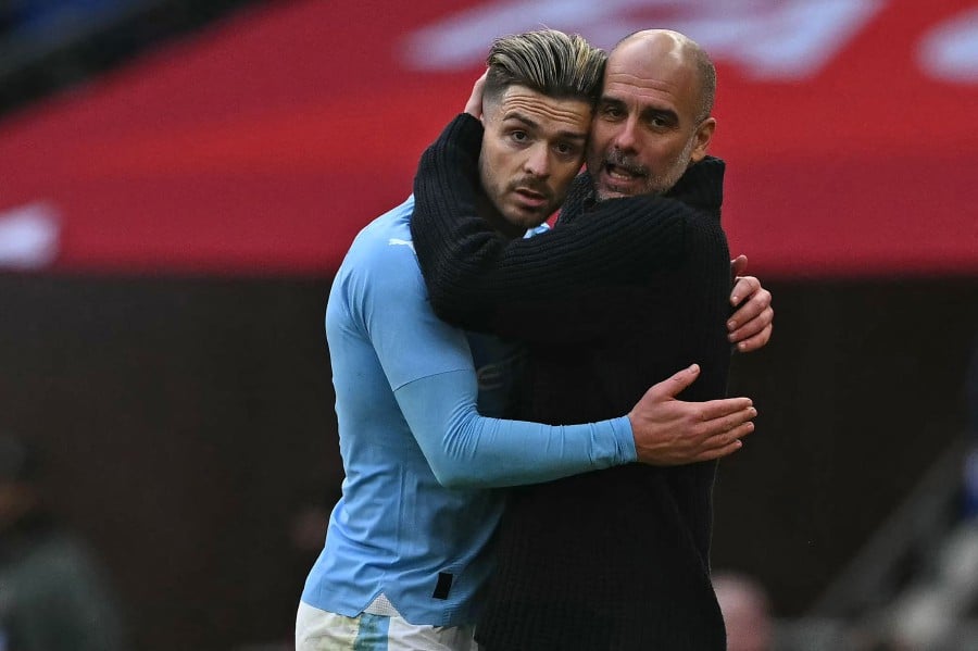 Manchester City's Pep Guardiola (R) embraces Jack Grealish (L) after substituting him during the English FA Cup semi-final football match between Manchester City and Chelsea at Wembley Stadium. - AFP PIC