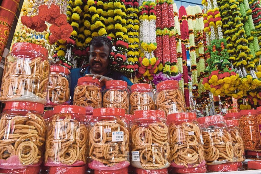 Subham store worker C. Periasamy arranging jars of murukku at a Deepavali display in George Town, Penang, yesterday. These festive treats were often hand-made the traditional way by the women of estate households in bygone years. BERNAMA PIC