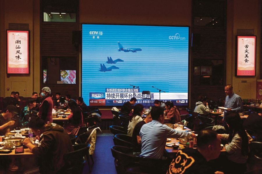 Customers dine near a giant screen broadcasting news footage of aircraft of the Air Force under the Eastern Theatre Command of China's People's Liberation Army (PLA) taking part in a combat readiness patrol and "Joint Sword" exercises around Taiwan, at a restaurant in Beijing, China. - REUTERS PIC