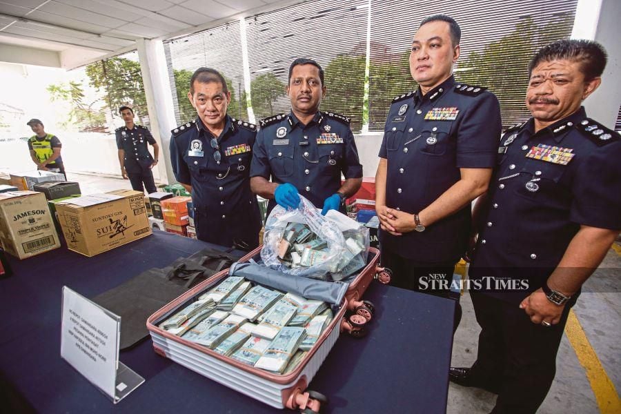 Selangor police chief Datuk Hussein Omar Khan (second from left) with his officers shows a bag filled with close to half a million Ringgit in cash, during a press conference on March 21 at the Subang Jaya district police headquarters. — NSTP/ HAZREEN MOHAMAD