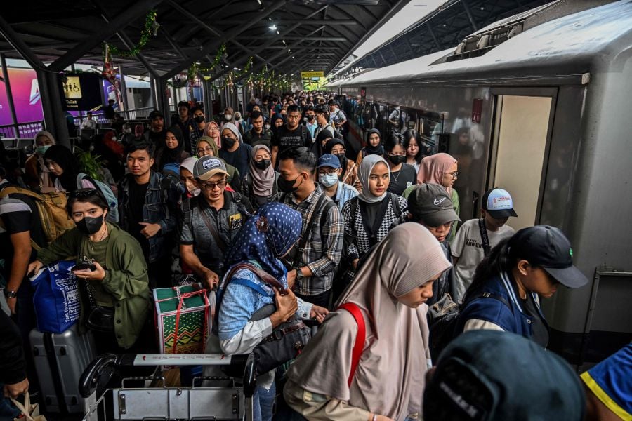 Passengers prepare to board a train for their long distance train to return home ahead of Eid al-Fitr, which marks the end of the Muslim fasting month of Ramadan, at Gubeng station in Surabaya. - AFP PIC