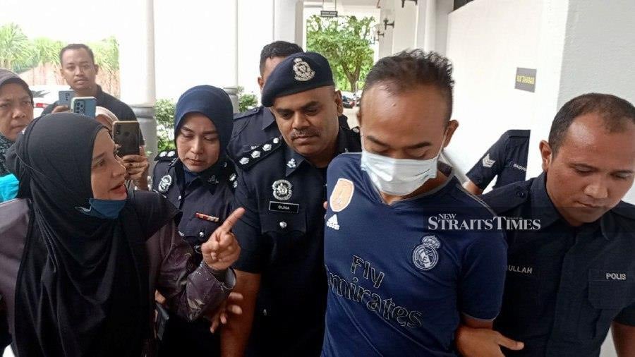 Rozita Radzuan (left) confronts her son-in-law Hairil Anaas Abdullah as police escort him from the Batu Gajah Magistrate’s Court yesterday. NSTP/MUHAMAD LOKMAN KHAIRI 