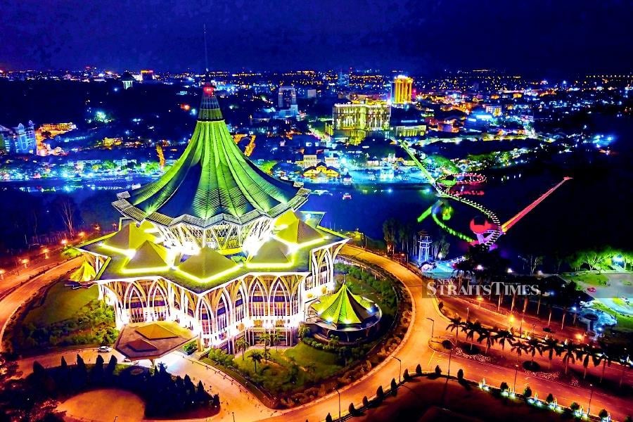 A view of Kuching, the state capital, at night. On the foreground is the state assembly building and the Darul Hana bridge across Sungai Sarawak.