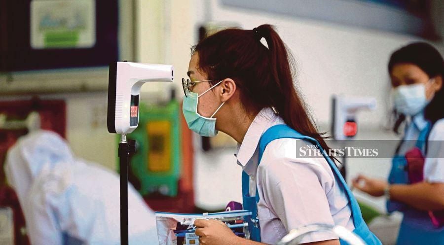 A student in Kuching checking her temperature before entering the hall to sit the Sijil Pelajaran Malaysia examination in February. An expert says the Education Ministry must present clear and easily understood SOP for the reopening of schools. FILE PIC 