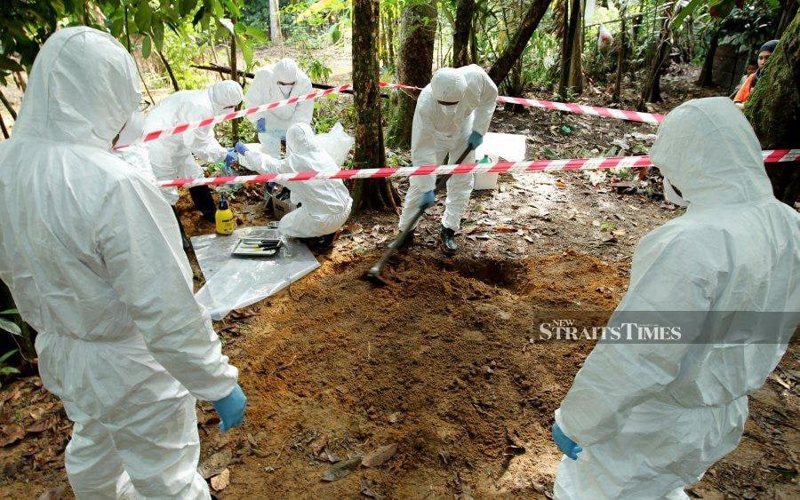 A file pic showing Kelantan Veterinary and Health Department officers sanitising a pit where culled chickens are supposed to be buried. - NSTP file pic