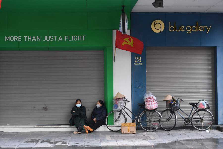 Women sit in front of closed stores in Hanoi. - AFP Pic