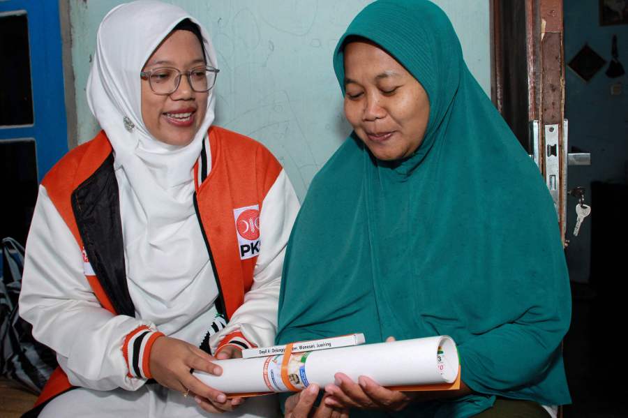 This photo taken on January 18, 2024 shows Lingga Permesti (L), a legislative candidate for the Islamic Prosperous Justice Party (PKS), presenting a calendar to a resident during house visitations ahead of the election in Klaten, Central Java. - AFP pic
