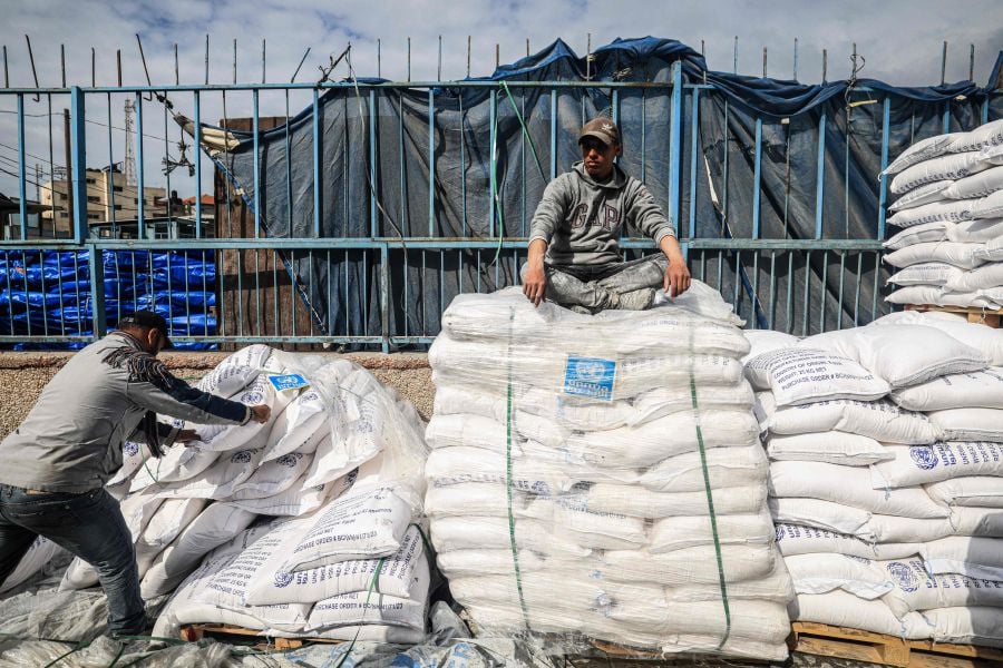 A worker rests as displaced Palestinians receive food aid at the United Nations Relief and Works Agency for Palestine Refugees (UNRWA) center in Rafah in the southern Gaza Strip on January 28, 2024.- AFP pic