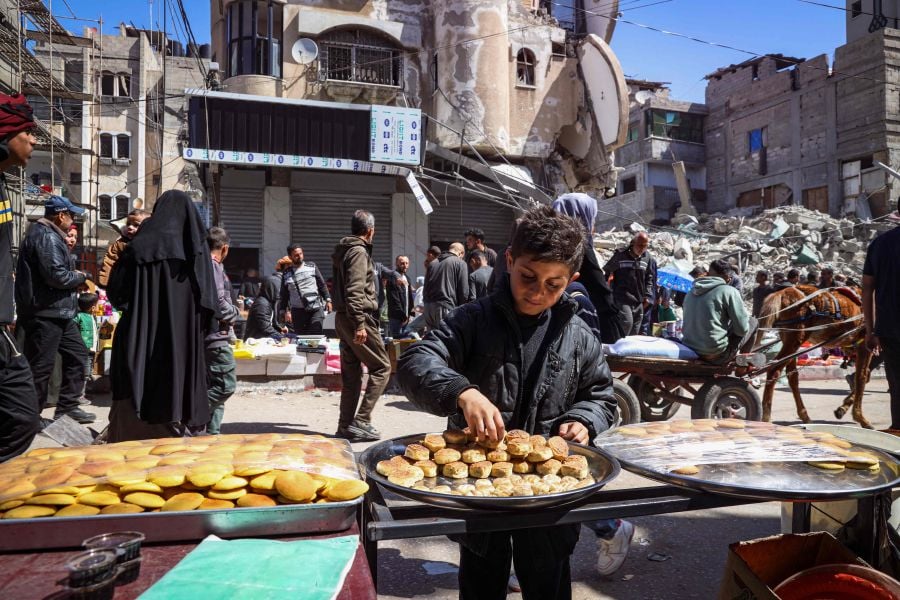 A Palestinian youth sorts a tray at a street stall selling traditional sweets during the Muslim holy fasting month of Ramadan in Rafah in the southern Gaza Strip on March 12, 2024. - AFP pic