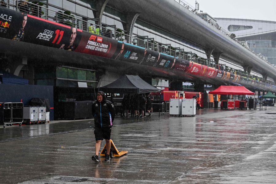 Formula one teams members walk down the rain next to the paddock at the Shanghai International circuit ahead of the Formula One Chinese Grand Prix, in Shanghai, on April 17, 2024. - AFP pic