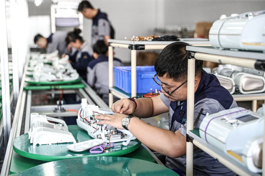 This photo taken on May 18, 2021 shows workers producing non-invasive ventilators at a factory in Shenyang, in China's northeastern Liaoning province. (Photo by STR / AFP)