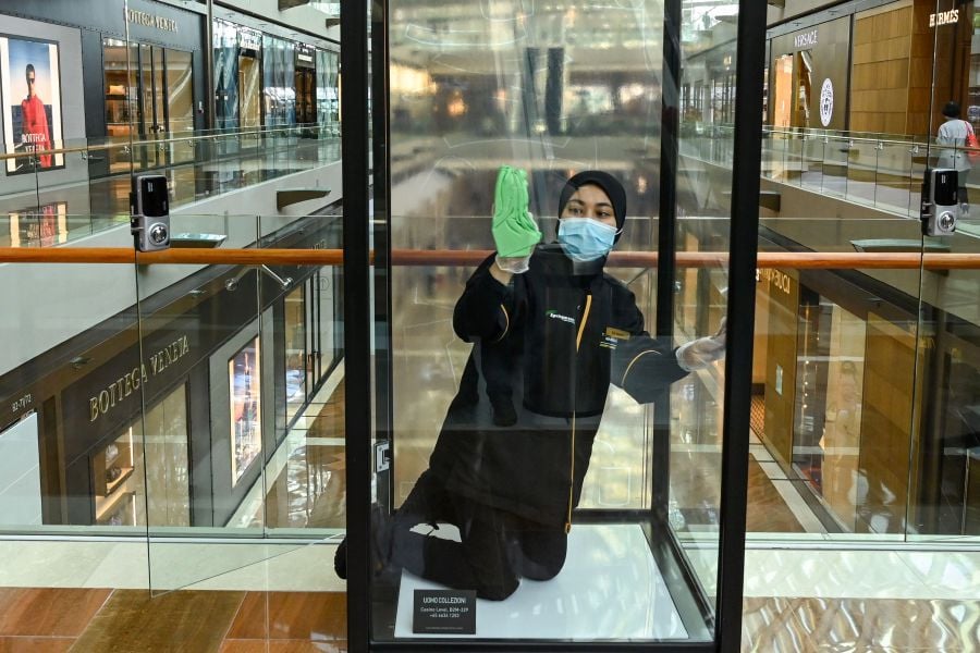 A cleaner wipes a display case at The Shoppes at Marina Bay Sands shopping mall in Singapore on June 19, 2020 as retail shops reopen in Singapore following the further easing of restrictions that were in place due to the COVID-19 novel coronavirus. (Photo by Roslan RAHMAN / AFP)