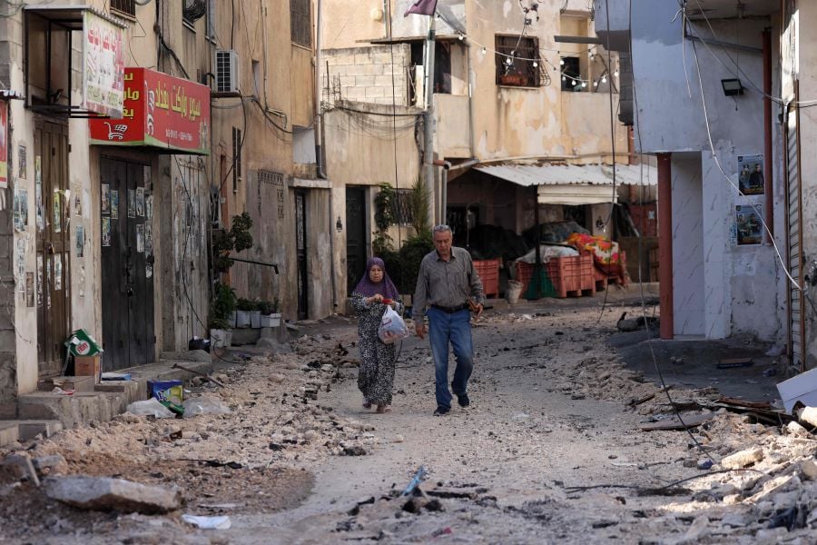 A couple walks in a street in the Jenin refugee camp, occupied West Bank, on July 4, 2023, after an Israeli military operation. - AFP Pic