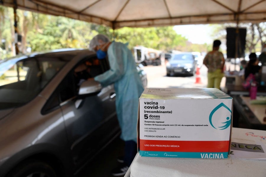 A health worker administers a dose of the AstraZeneca/Oxford COVID-19 vaccine to a man at a drive-thru vaccination post in Brasilia. - AFP Pic