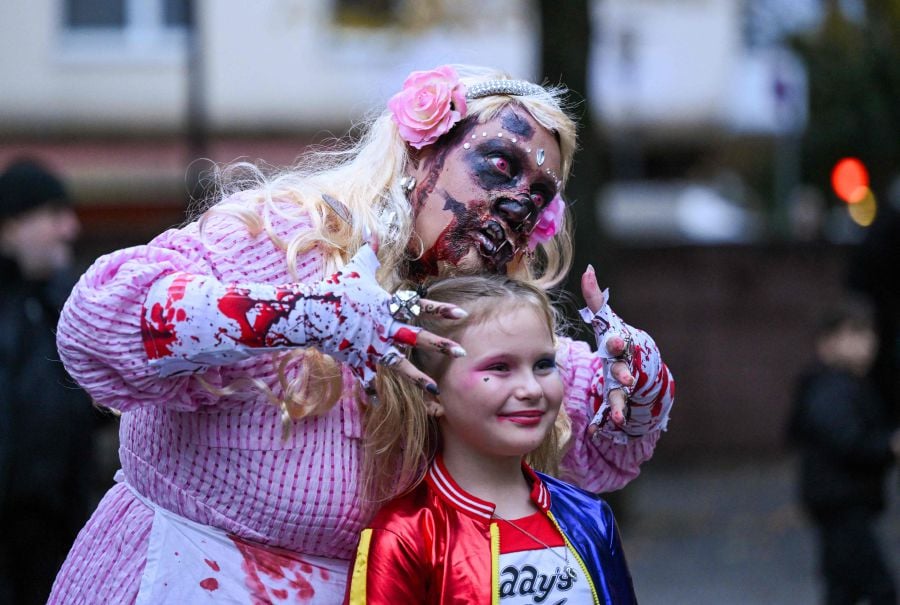 A woman wearing a Halloween costume representing a Barbie poses with a girl during the 'Zombie Walk' in Essen, western Germany on October 31, 2023. - AFP Pic