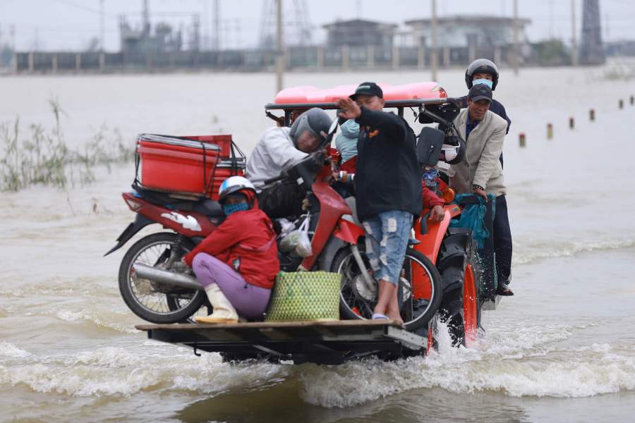 Residents are carried on a forklift truck to dry land through flood waters brought by heavy rain from Typhoon Vamco after it made landfall in Thua Thien Hue province on November 15, 2020. (Photo by Huy THANH / AFP)