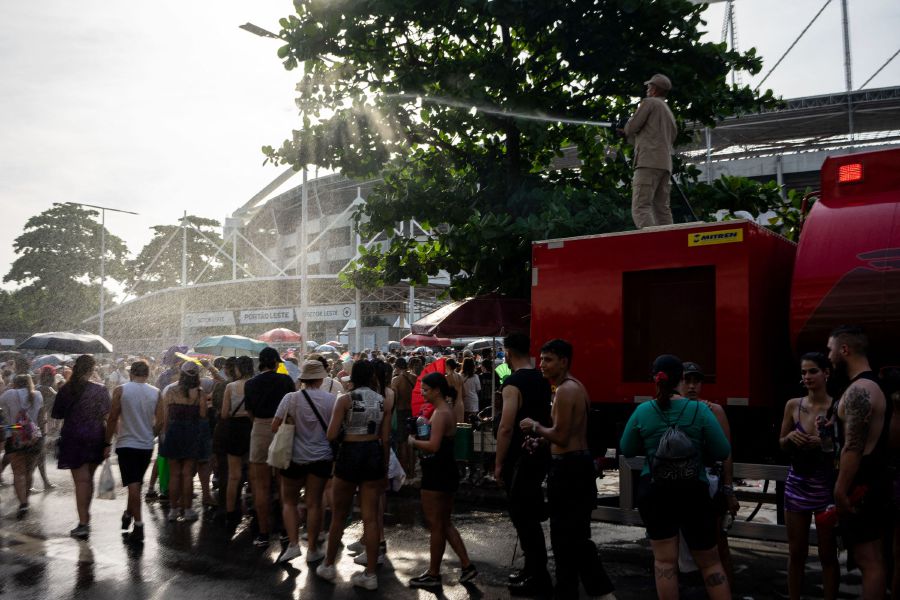 A firefighter cools off fans of US singer Taylor Swift with a hose as they queue outside the Nilton Santos Olympic Stadium before Swift's concert, "Taylor Swift: The Eras Tour", amid a heat wave in Rio de Janeiro on November 18, 2023. - AFP Pic