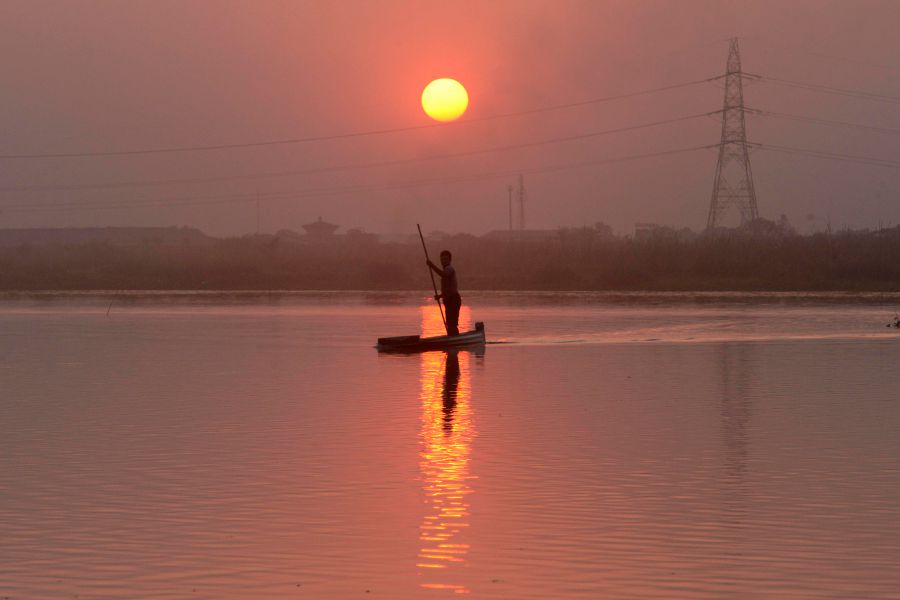 A fisherman rows a boat at the Fulbari wetland area on the outskirts of Siliguri. (Photo by DIPTENDU DUTTA / AFP)