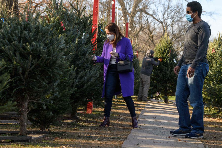 People shop for a Christmas tree at Saint Sophia Greek Orthodox church in Washington, DC, two weeks before Christmas on December 11, 2020. (Photo by Nicholas Kamm / AFP)