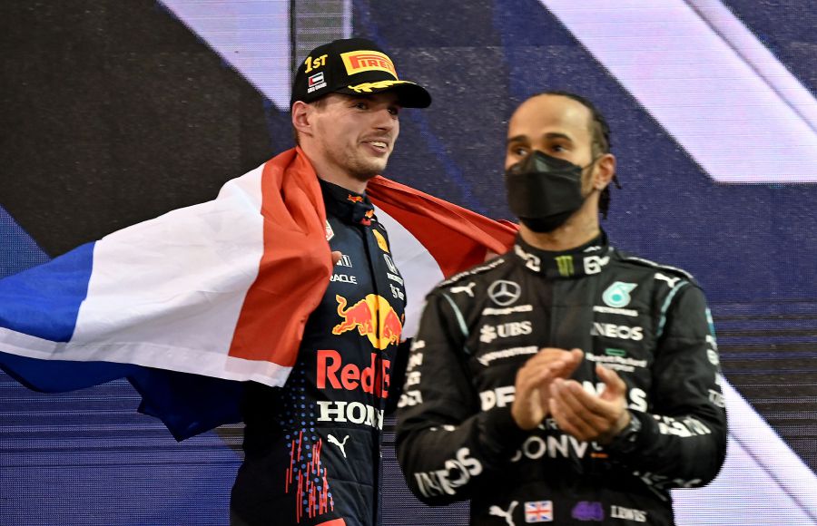 2021 FIA Formula One World Champion Red Bull's Dutch driver Max Verstappen walks past second-placed Mercedes' British driver Lewis Hamilton (R) on the podium of the Yas Marina Circuit after the Abu Dhabi Formula One Grand Prix on December 12, 2021. - AFP Pic