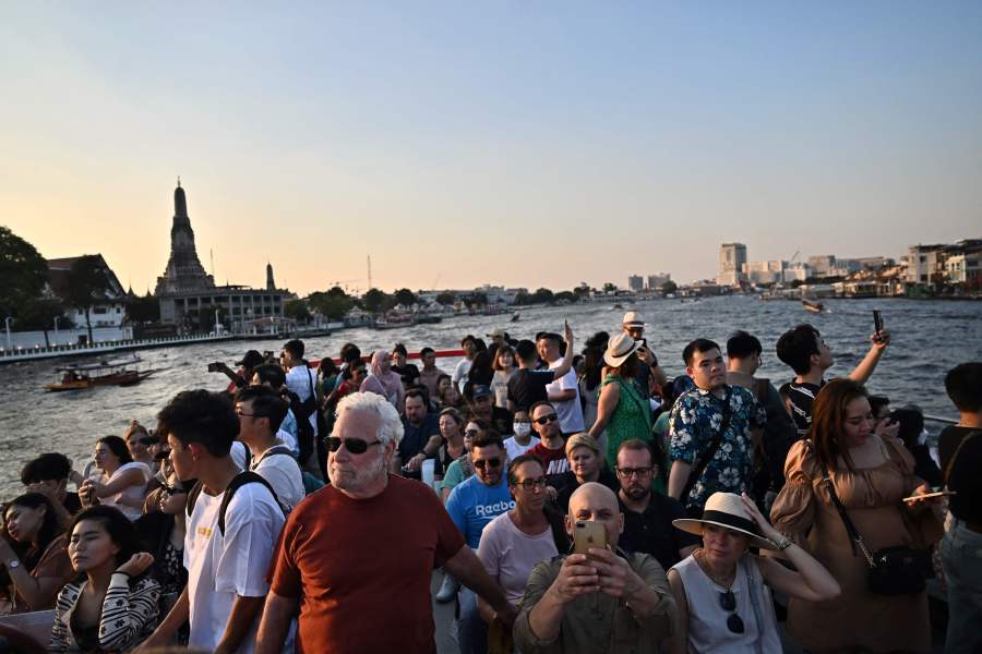 Tourists and locals look at the view from the top deck of a tourist commuter boat on the Chao Praya River in Bangkok on December 27, 2023. - AFP pic