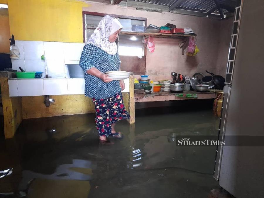 In Kuala Sungai Baru, food trader Aminah Dayah kept cooking even as water rose around her stall. - NSTP/HASSAN OMAR 