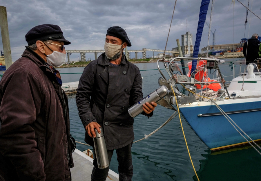 Handout picture released on June 21, 2020 by Telam, of Argentine Juan Manuel Ballestero (R) speaking with his father Carlos (L) upon arrival in Mar del Plata, from Portugal, on June 20, 2020, after sailing for 85 days due to the COVID-19 pandemic restrictions. - Having tested negative for COVID-19 upon arrival, Ballestero was cleared to set foot on dry land to stay with his parents, 82-year-old Nilda and Carlos, aged 90. (Photo by Diego Izquierdo / TELAM / AFP) 