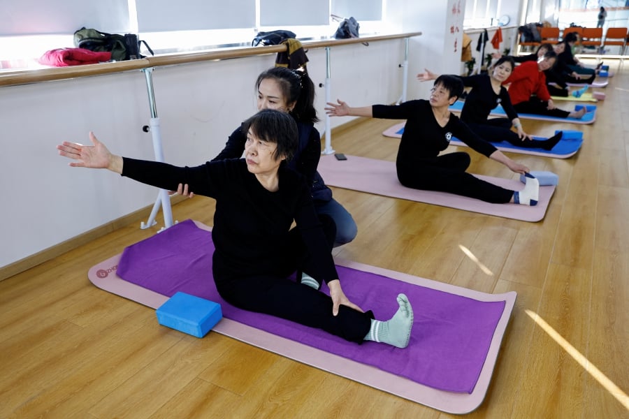 A teacher coaches an elderly person during a yoga class at Mama Sunset, a learning centre for middle-aged and senior people in Beijing, China. (REUTERS/Tingshu Wang)