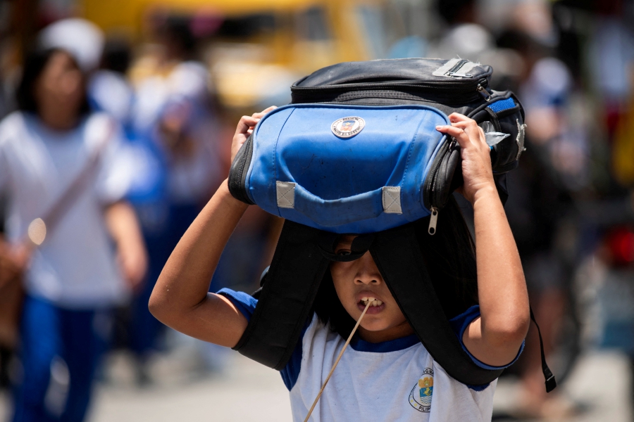 A student uses her bag as protection against the sun, outside an elementary school in Manila, Philippines. (REUTERS/Lisa Marie David)