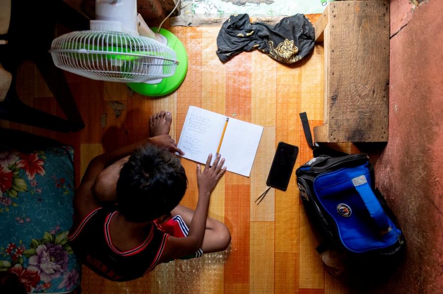 A student answers his learning module following the suspension of in-person classes, inside his house in Manila, Philippines. (REUTERS/Lisa Marie David)