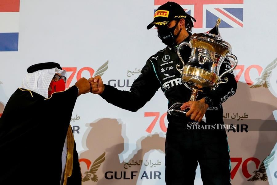 Mercedes' British driver Lewis Hamilton is congratulated by a Bahraini official on the podium after the Bahrain Formula One Grand Prix at the Bahrain International Circuit in the city of Sakhir on Nov 29.  (Photo by HAMAD I MOHAMMED / POOL / AFP)