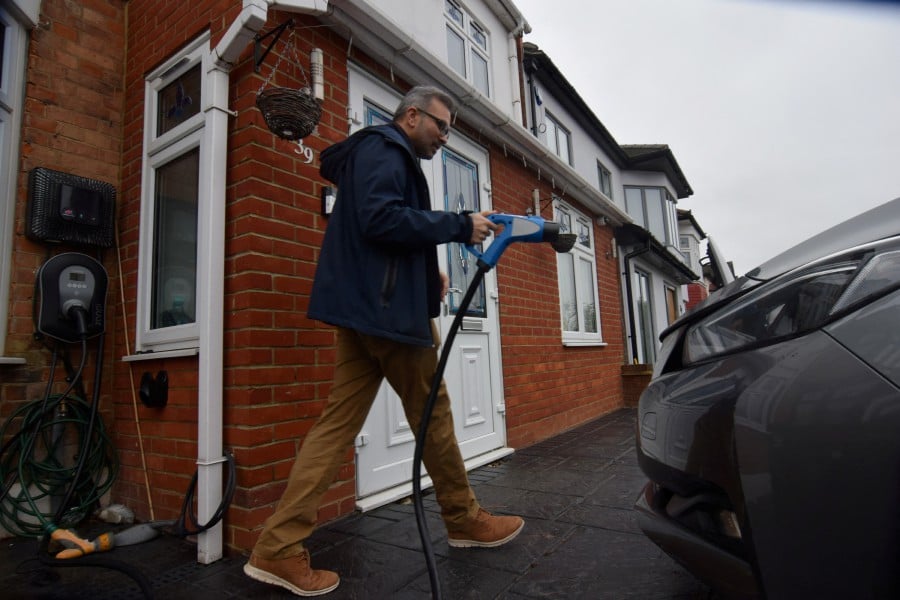 Shilpen Patel walks to plug in his bidirectional electric Nissan Leaf, which is able to power his home and provide power back to the grid, at his house in London, Britain. -- Reuters photo