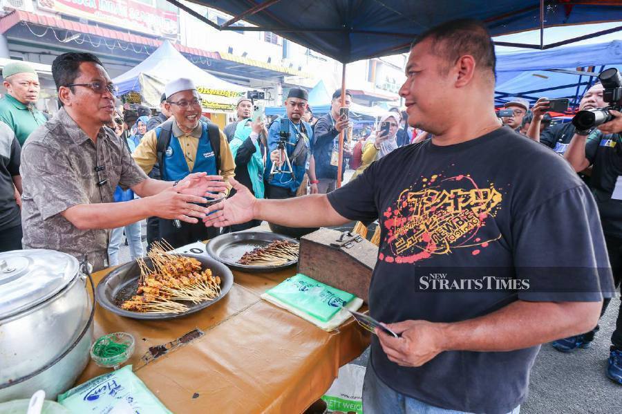Perikatan Nasional candidate for the Sungai Bakap by-election Abidin Ismail (left) meeting voters at the Taman Pekatra pasar malam. NSTP/DANIAL SAAD